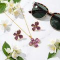Parure fleur or et email violet mauve sur marbre avec fleurs de jasmin et lunettes de soleil